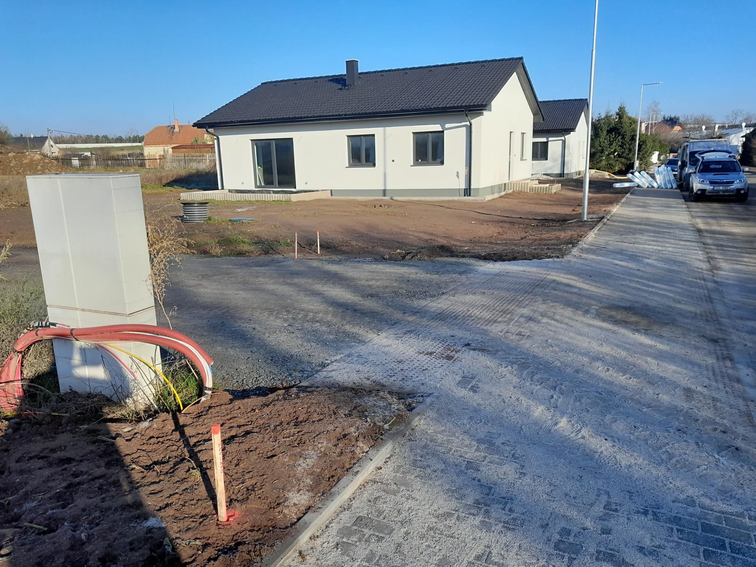 Novostavba rodinného domu na upravené parcele s vytyčovacím kolíkem v popředí